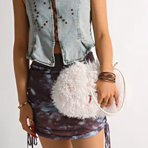 Close-up detail of a soft white faux sheep fur cloud bag held by a fashion model