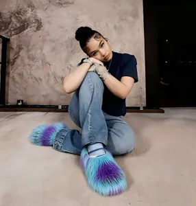 Stylish faux fur monster claw slippers with metallic nails on a model in a trendy setting