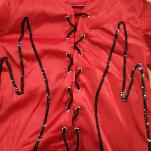 Dettaglio costume vampiro gotico in satin rosso, paillettes nere, allacciatura.