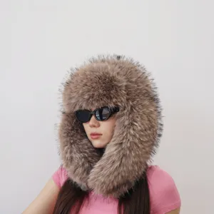 Close-up of a model wearing a large fluffy brown faux raccoon fur Y2K style ski hat