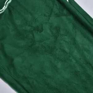 Close-up detail of dark green velvet fabric with white stitching for festival costume.