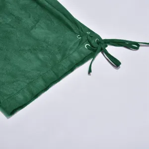 Green velvet garment detail with metal eyelets and lace-up drawstring for festive wear.
