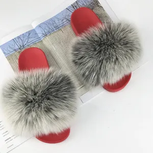 Dettaglio della morbida pelliccia grigia di procione su ciabatte rosse alla moda.
