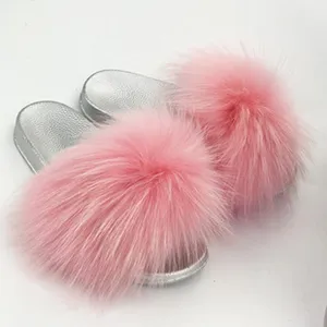 Dettaglio delle ciabatte in pelliccia rosa con suole metallizzate in PVC argento.