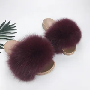 Dettaglio di pantofole in pelliccia bordeaux con suole in PVC