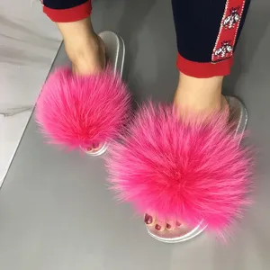 Close-up of bright pink raccoon fur slides featuring a sparkling silver PVC sole.