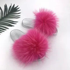 Detail of silver PVC slides with large fluffy pink raccoon fur poms for summer fashion