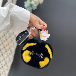 Close-up van een schattige zwart-gele pluche katten-sleutelhanger met autosleutels
