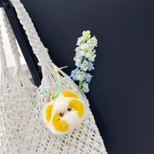 Close-up van een schattige gele pluche kattenbedel aan een stijlvolle macramé tas