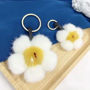 Detailansicht der weichen weiß-gelben Nerzfell-Blumenanhänger mit goldenen Ringen
