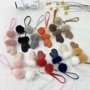 Assortment of colorful glove-shaped keychains with fur pom-poms and leather detail