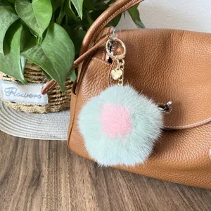 Close-up of a mink fur flower bag charm with a pink center on a brown leather bag.