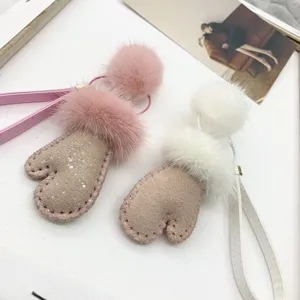 Close-up of cute mitten-shaped keychains with soft faux mink fur trim and leather straps