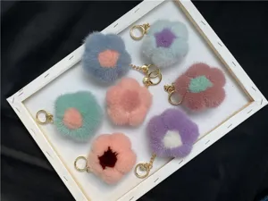 Close-up view of colorful mink fur flower keychains arranged in a white decorative tray.