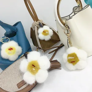 Nahaufnahme von flauschigen Nerzpelz-Eierblumenanhängern an modischen Designer-Handtaschen