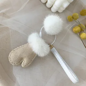 Close-up of a cute mink fur mitten keychain with white pom-pom for bag charm accessory