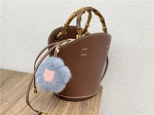 Close-up of a blue and pink mink fur flower keychain attached to a brown bag