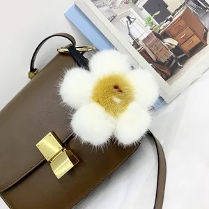 Nahaufnahme eines weiß-gelben Nerzfell-Blumenanhängers an einer braunen Ledertasche.