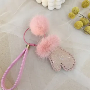 Close-up detail of a cute pink mink fur pom and glittery mitten keychain bag charm