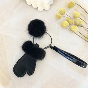 Close-up of black faux fur mitten and pom-pom keychain charm for bags and car keys.
