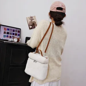 Detailansicht der weißen Schultertasche aus Nerzimitat mit einem cremefarbenen Pullover