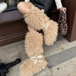 Gros plan de bottes en fausse fourrure frisée avec brides à clous et boucles style punk.