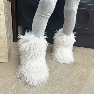 Gros plan de bottes de neige blanches en fausse fourrure pour enfants au style shaggy.