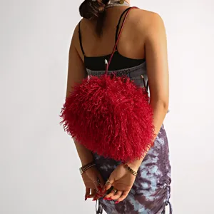 Close-up of vibrant red faux lamb wool fuzzy cloud bag worn by a model from the back