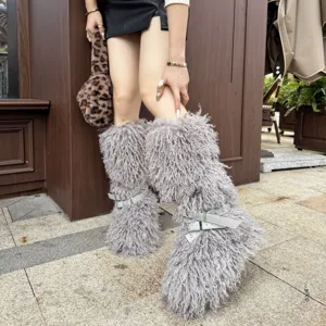 Gros plan de bottes grises en fausse fourrure à poils longs avec brides à boucles blanches.