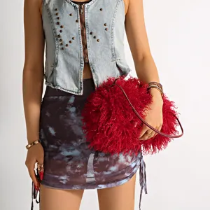 Close-up view of a stylish fluffy deep red faux fur cloud bag held by a fashion model