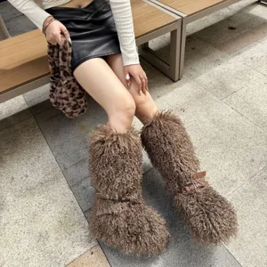 Gros plan de bottes de neige en fausse fourrure frisée avec brides à boucle en cuir