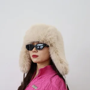 Nahaufnahme eines Models mit einer dicken beigen Y2K-Ushanka aus Kunstfuchsfell.