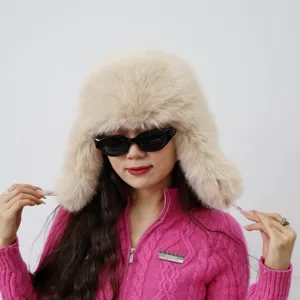 Modell trägt eine dicke beige Kunstpelz-Ushanka mit stilvoller schwarzer Sonnenbrille