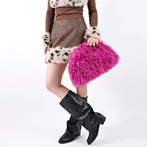 Model holding a vibrant magenta fluffy faux fur cloud clutch bag with plush texture