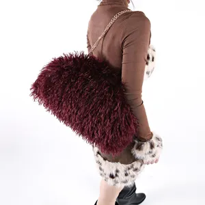 Oversized burgundy faux fur crossbody bag with gold chain strap shown on a model
