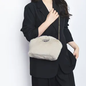 Λεπτομέρεια της μπεζ τσάντας clutch από ψεύτικη γούνα με κομψή χρυσή αλυσίδα