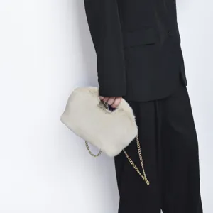 Λεπτομερής προβολή κομψής τσάντας clutch από κρεμ ψεύτικη γούνα με χρυσή αλυσίδα