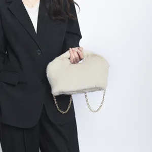 Λεπτομέρεια μίας κομψής μπεζ τσάντας clutch από συνθετική γούνα με χρυσή αλυσίδα