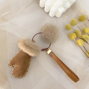 Close-up of a cute brown faux suede mitten keychain with a soft mink fur pom-pom.