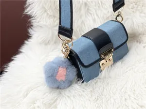Detailed close-up of a blue mink fur flower charm attached to a denim shoulder bag