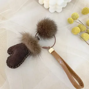 Close-up of cute brown mitten keychain featuring real mink fur pom pom and leather strap
