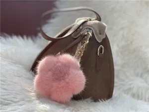 Detailed view showing a soft pink mink fur flower charm accessory on a brown suede bag
