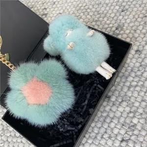 Macro detail of fluffy mink fur flower and doll bag charms in a black gift box