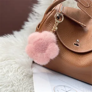 Soft pink mink fur flower bag charm and keychain accessory on a brown leather handbag