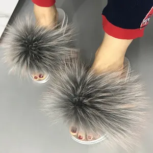 Detailed view of the fluffy grey raccoon fur and silver glitter PVC sole of the slipper