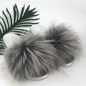 Detailed view of fashionable silver PVC sole slides with voluminous grey raccoon fur