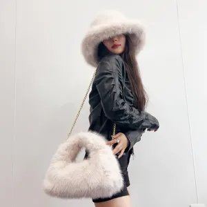 Stylish lifestyle view of a model wearing a plush faux fox fur bucket hat and hobo bag.