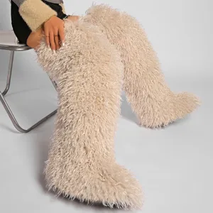 Primer plano de botas de nieve beige de piel de oveja sintética sobre la rodilla.