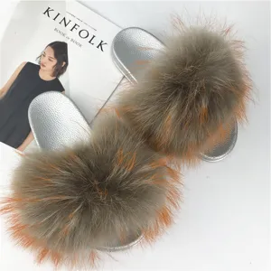 High-resolution detail of fluffy raccoon fur slippers with metallic silver PVC soles.