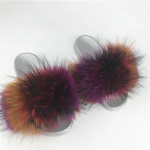 Close-up of fluffy multi-colored fur slides with shimmering silver PVC soles.